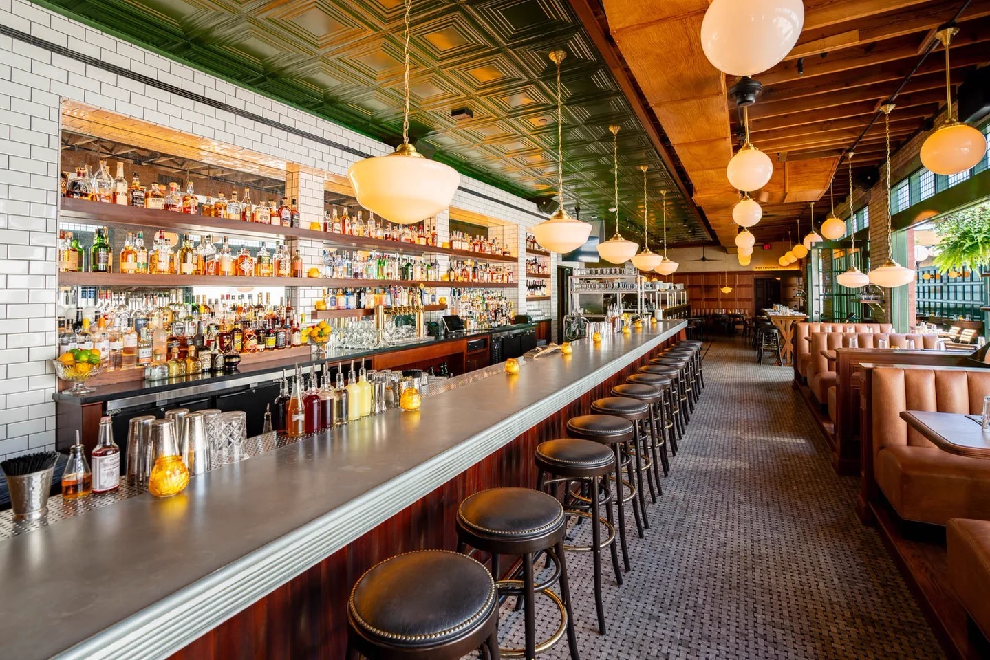A La Bastille zinc bar top running the length of a restaurant bar under glass pendant lights